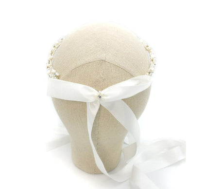 Beige fabric ring cushion with a white ribbon on a white background