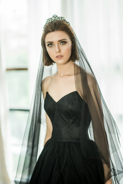 Woman wearing a black dress with a long black veil and tiara indoors